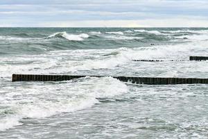 uitzicht op blauwe zee met schuimende golven en houten golfbrekers foto