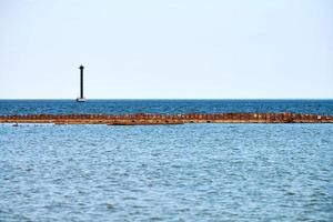 oud verlaten roestig zee pier voor afmeren boten en jachten Aan achtergrond van kalmte blauw zee, horizon foto