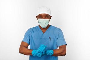 zwart chirurg dokter Mens in blauw jas wit pet chirurg masker steriliseert blauw handschoenen wit achtergrond foto