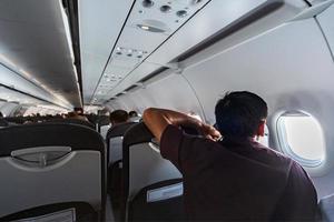 Mens looks in vliegtuig venster. nieuw vliegtuig cabine met comfortabel stoelen. economie klasse vlucht van nieuw vliegmaatschappij zonder vlucht vertraging. foto
