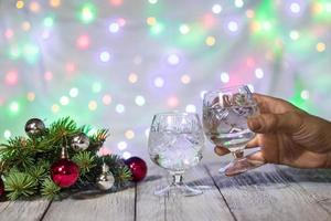 hand- Holding een glas van Champagne Aan een tafel opnieuw Kerstmis fee lichten bokeh Aan achtergrond foto