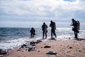 silhouetten van scuba verschillend Aan de kust. diepte ontdekkingsreizigers bereiden naar duiken naar de bodem foto