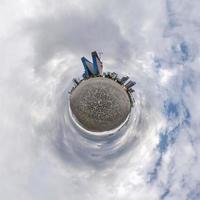 klein planeet in blauw lucht met wolken in stad strand in de buurt modern wolkenkrabbers of kantoor gebouwen. transformatie van bolvormig 360 panorama in abstract antenne visie. foto