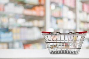 leeg winkelmandje op de teller van de apotheekdrogisterij met onduidelijke planken van geneeskunde en vitaminesupplementenachtergrond foto