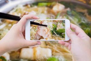 vrouw die foto van sukiyaki shabu shabu . neemt