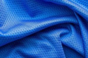 blauwe kleur stof sportkleding voetbal trui met lucht mesh textuur achtergrond foto