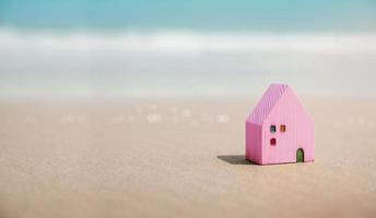 strand huis concept. mini kleurrijk houten huis Aan de zand strand. bestemming voor vakantie of pensioen leven. zomer zonnig dag. metafoor foto