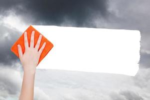 hand- verwijdert regenachtig wolken van lucht door oranje vod foto
