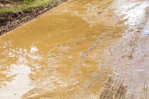 modder en plas in sleur van aarde grond weg foto