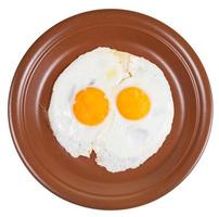 top visie van twee gebakken eieren Aan keramisch bruin bord foto