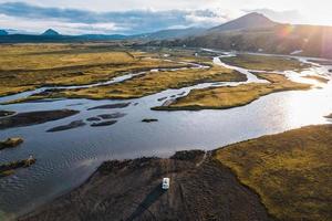 vier wiel rit voertuig geparkeerd door de groot rivier- kruispunt in de avond Aan afgelegen landelijk Bij IJslands hooglanden foto