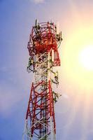 telecom toren met zender antenne Aan de helder blauw lucht en zon gloed achtergrond. foto