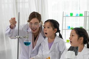 Aziatisch kinderen leren chemie en wetenschap in laboratorium met leraar foto