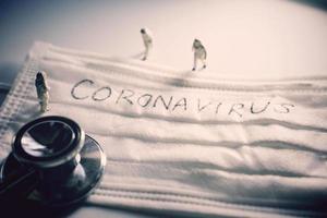 miniatuur mensen artsen met beschermend pak het voorkomen van pandemisch covid-19 en coronavirus, chirurgisch masker met coronavirus tekst geschreven Aan het met stethoscoop, dramatisch afgezwakt foto