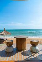 hout tafel stoel en stoel met zee strand achtergrond foto