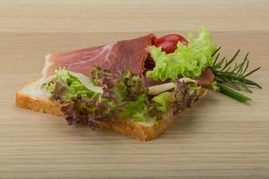 prosciutto belegd broodje Aan houten bord en houten achtergrond foto