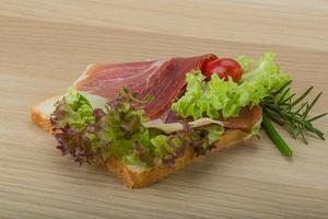 prosciutto belegd broodje Aan houten bord en houten achtergrond foto