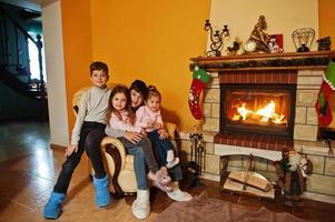 gelukkige vier kinderen thuis bij een open haard in warme woonkamer op winterdag. foto