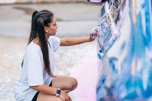 brunette met twee vlechten met een spons wast de kant van de auto foto