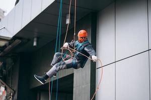 industrieel klimmer in uniform en helm stijgt foto