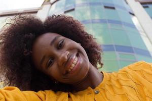 een gelukkige en jonge Afro-Amerikaanse vrouw neemt een selfie, close-up foto