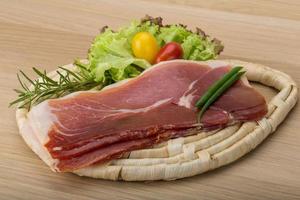 prosciutto Aan houten bord en houten achtergrond foto