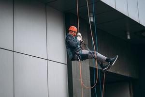 industrieel klimmer in uniform en helm stijgt foto