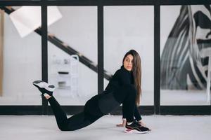 jong vrouw vervelend zwart sport- pak oefenen yoga houding binnenshuis. foto