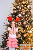 portret van weinig meisje vervelend hert Kerstmis hoed. winter vakantie en mensen concept. foto