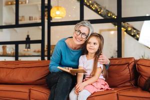 mooi hoor ouderen vrouw grootmoeder lezing verhaal naar kleindochter. foto