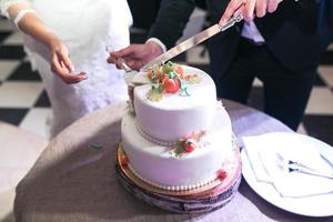 de bruid en bruidegom besnoeiing de bruiloft mooi taart foto