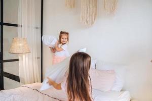 twee weinig meisjes spelen met kussens in slaapkamer foto