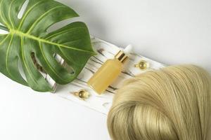 een natuurlijk essentieel olie of serum voor haar- zorg aan het liegen Aan een wit houten dienblad. haar- zorg en gladmaken concept foto