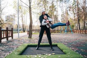 mam en haar dochter jumping samen Aan trampoline in herfst park foto
