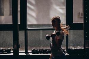 slank atletisch meisje presteert fysiek opdrachten met halters. foto