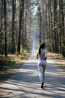 mooi jong vrouw rennen in groen park Aan zonnig zomer dag foto