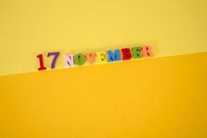 17 november Aan een geel en papier achtergrond met houten en veelkleurig brieven met ruimte voor tekst. foto