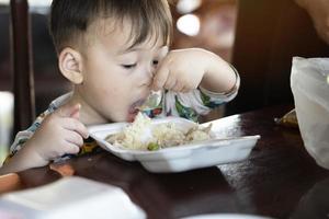 schattig weinig jongen is aan het eten voedsel gelukkig. kind gelukkig eet ontbijt. foto