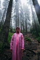 jong vrouw in een regenjas wandelingen door de Woud in de regen foto