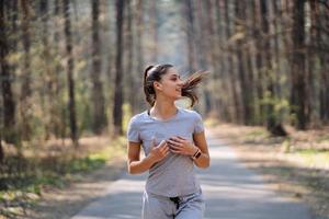 mooi jong vrouw rennen in groen park Aan zonnig zomer dag foto