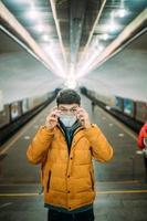 vent staand Bij station in medisch beschermend masker Aan zijn gezicht. foto