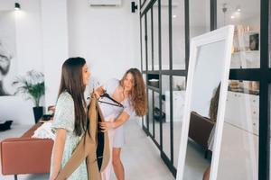 twee Dames Kiezen en proberen Aan kleren Bij huis foto