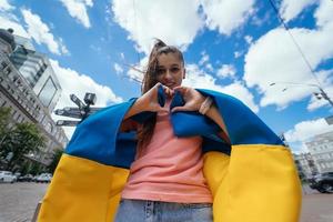 jong vrouw met oekraïens vlag shows hart met handen foto