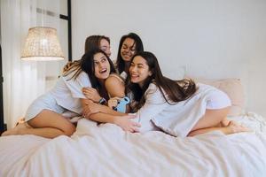 positief jong meisjes Dames vrienden binnenshuis Aan bed Bij de kip partij Bij huis. foto