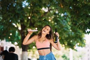 jong vrouw draagt een bord van snacks en een drinken in handen foto