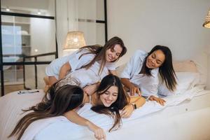 positief jong meisjes Dames vrienden binnenshuis Aan bed Bij de kip partij Bij huis. foto