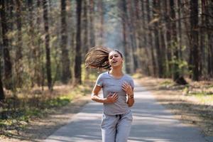 mooi jong vrouw rennen in groen park Aan zonnig zomer dag foto