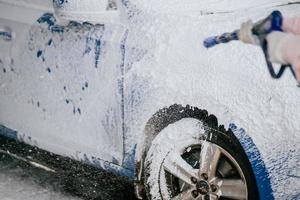 brunette van een hoge druk slang is van toepassing een schoonmaakster Aan de auto foto