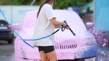 brunette van een hoge druk slang is van toepassing een schoonmaakster Aan de auto foto