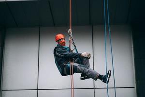 industrieel klimmer in uniform en helm stijgt foto